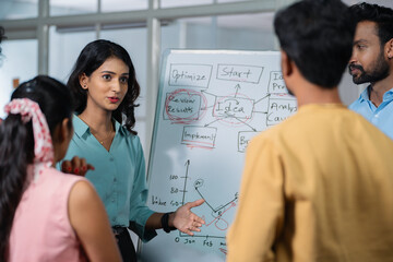 young girl at office discussing about project to team members or colleagues during meeting - concept of leadership presentation, workplace communication and startup culture.