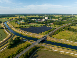 Fototapeta na wymiar Drone Shot of solar panels at a sunny day between fields, river and a street.