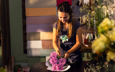 Young woman working in her flower shop making bouquet.