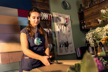 Young woman working in her flower shop making bouquet.