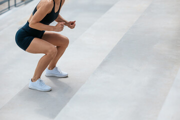 Woman in black sports shorts doing squats on the stairs