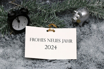 Frohes Neues Jahr 2024: Glücksschwein, Wecker  und einer Karte mit Glückwünschen für das neue...