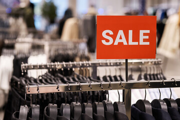 Closeup of red sale banner attached to clothing rack at shop