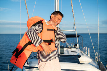 Man on a yacht putting on a life jacket