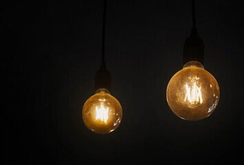 Light bulb hanging in a dark room. Household electricity consumption. Ideas and problem solving.
