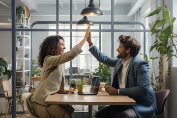 coworkers sharing a high - five in a modern, creative office space