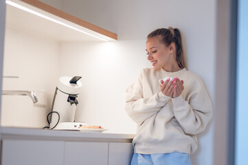 Smiling cute girl having coffee in the kitchen