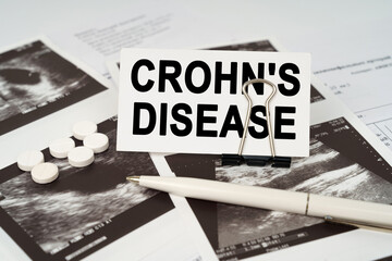 On the ultrasound pictures there is a pen and a business card with the inscription - Crohns disease - obrazy, fototapety, plakaty
