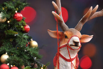 Christmas reindeer with rope to pull a sleigh, Christmas pine tree and background with blurred...
