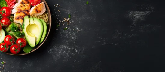 Fototapeten Grilled chicken quinoa spinach avocado brussels sprouts tomatoes cucumbers in a healthy buddha bowl viewed from the top on a dark gray background Copy space image Place for adding text or desig © vxnaghiyev