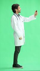 male doctor in a white coat on a green background looking at the phone