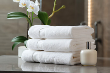 A stack of clean cotton towels on a table in the bathroom. White terry towels.