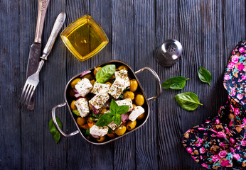 feta cheese with olives and olive oil sauce in bowl on dark background.