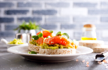 open sandwiches with rye bread, avocado, smoked salmon on a white plate