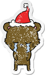crying hand drawn distressed sticker cartoon of a bear wearing santa hat