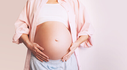 Closeup beautiful pregnant woman belly with her hands. Pregnancy, maternity, preparation and expectation concept.
