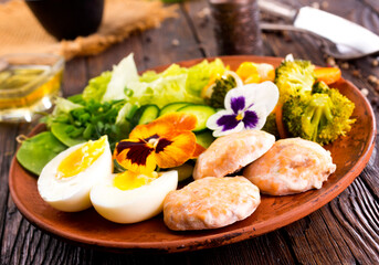Fried salmon cutlets on a plate with vegetables and boiled eggs