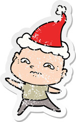 hand drawn distressed sticker cartoon of a nervous man wearing santa hat