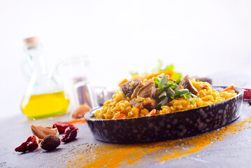 Pilaf, a dish of rice, chicken, carrots with spices and dried cranberries on a black plate