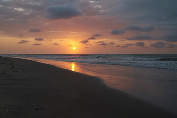 Sunset on the beach in Tumbes, Peru with waves and sand.