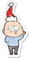 hand drawn distressed sticker cartoon of a bald man staring wearing santa hat