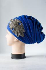 Blue turban on a mannequin head, pleated blue fashion turban on a white background