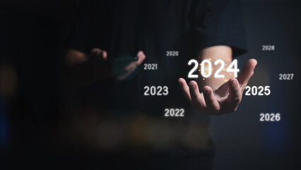 The virtual 2024 year on hand with other years scattered around. The new year 2024. Concept of new...