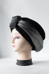 Grey turban on a mannequin head, pleated Grey fashion turban on a white background