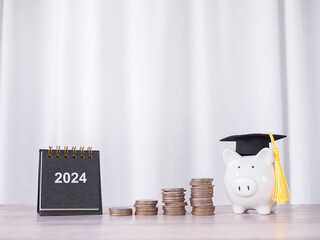 Study goals, 2024 Desk calendar, Piggy bank with graduation hat and stack of coins. The concept of...