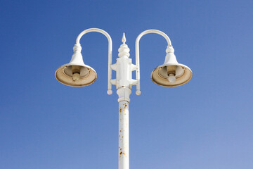 Victorian street light. Street lamp isolated on blue sky. White paint metal construction....