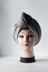 Grey turban on a mannequin head, pleated Grey fashion turban on a white background
