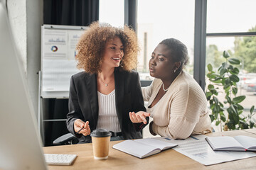 creative interracial businesswoman talking near notebooks and documents in modern office, teamwork