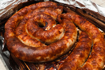 Spiral grilled homemade sausage. Baked homemade sausage close up. Delicious Bavarian sausages.
