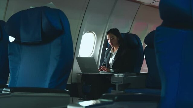 Successful Asian business woman, Business woman working in airplane cabin during flight on laptop computer