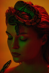 Stunning woman in a mix of red and green light, with a python snake gracefully positioned on her head like a crown