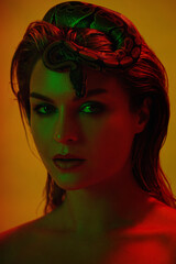 Stunning woman in a mix of red and green light, with a python snake gracefully positioned on her head like a crown