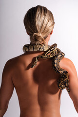 Young woman with python snake elegantly slithering over her neck