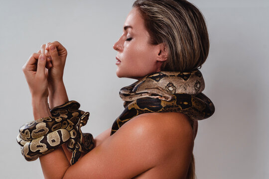 Beautiful woman with python snakes elegantly slithering over her neck and wrists