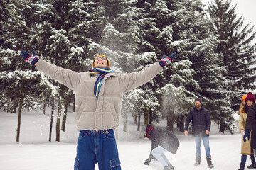 Happy diverse young people in outerwear play snowballs enjoy winter vacation in snowy park. Smiling friends have fun relax in frosty forest on active weekend outdoors. Activity and holidays.