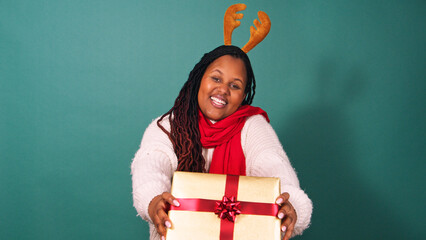 Beautiful Black woman shakes Christmas gift dancing, excited for present, studio