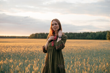 red-haired girl in a linen dress in a field