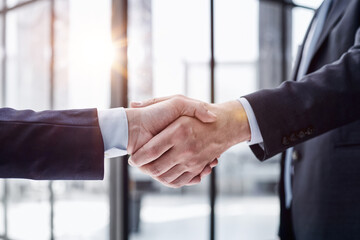 executives shaking hands in front of their manager and a colleague