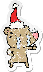 hand drawn distressed sticker cartoon of a crying bear wearing santa hat