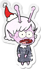 hand drawn distressed sticker cartoon of a shocked alien girl wearing santa hat
