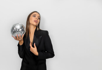 beautiful woman in black suit with shiny christmas disco ball in hand, on cyclorama background.wide banner for winter new year advertising.girl female leaning from high chair,minimalist