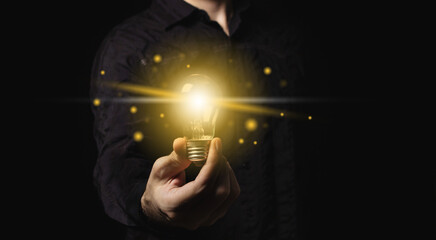 Man holding a light bulb in his hand, idea of creativity and inspiration concept of sustainable...