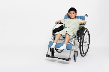 Fototapeta na wymiar Asian little boy kid sitting on wheelchair and wearing patient outfits isolated on white background, Personal child accident concept