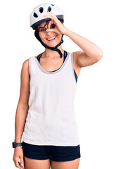 Beautiful young woman with short hair wearing bike helmet smiling happy doing ok sign with hand on eye looking through fingers