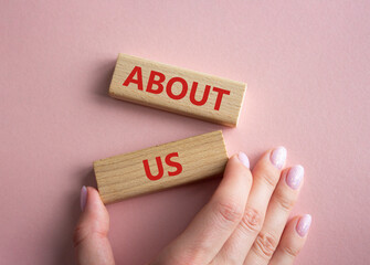 About us symbol. Concept word About us on wooden blocks. Businessman hand. Beautiful pink background. Business and About us concept. Copy space