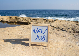 New job symbol. Concept words New job on white chalk background. Beautiful sea background. Business...